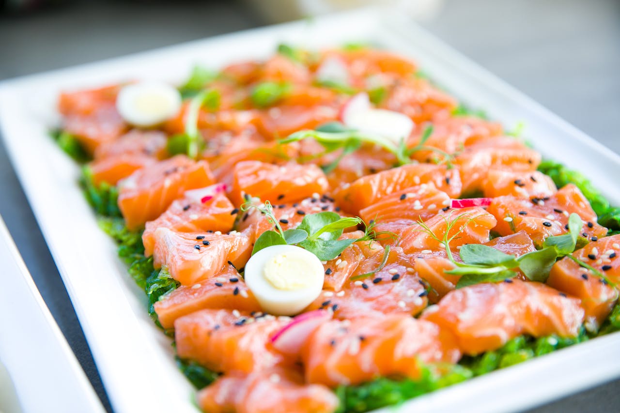 portfolio-03 Delicious salmon sashimi garnished with quail eggs and fresh greens on a platter.